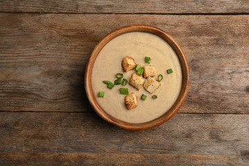 Bowl of fresh homemade mushroom soup on wooden background, top view