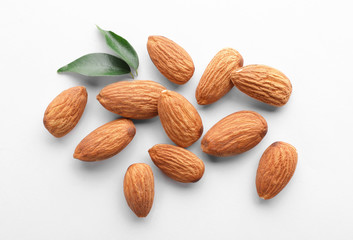 Organic almond nuts and leaves on white background, top view. Healthy snack