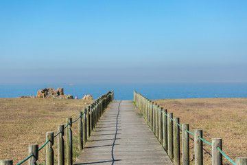 Perspective view of wooden pedestrian walkway, towards the ocean, next to the beach