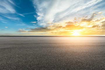 Asphalt road and dramatic sky with coastline at sunset