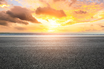 Asphalt road and dramatic sky with coastline at sunset