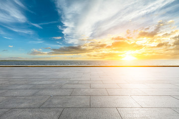 Empty square floor and dramatic sky with coastline at sunset