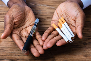 Man Holding Vape And Tobacco Cigarettes