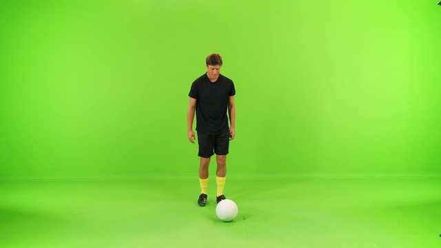 Soccer player juggling with a ball in a full shot over a green screen, high speed shutter, slow motion.