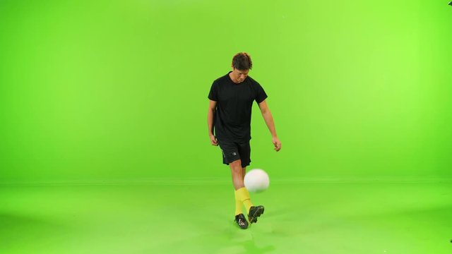 Soccer player looks into the camera and smiles while playing over a green screen, high speed shutter, slow motion, 3 takes.