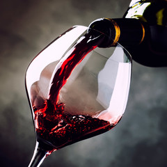 French dry red wine, pours into glass, gray background, selective focus