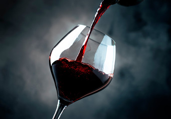 French dry red wine, pours into glass, gray background, selective focus