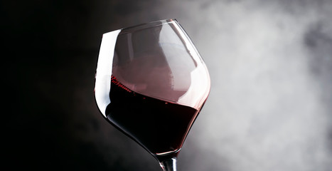Naklejka na ściany i meble Red wine, splash in a glass, dry cabernet sauvignon, dark background, defocused in motion image, shallow depth of field
