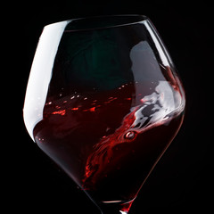 Red wine, splash in a glass, dry cabernet sauvignon, dark background, defocused in motion image,...