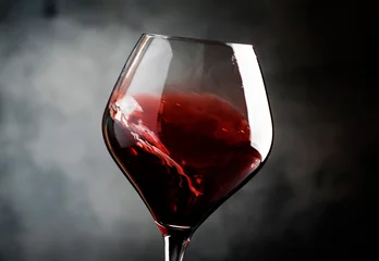 Foto auf Acrylglas Wein Spanischer trockener Rotwein, Spritzer im Glas, aus der Tempranillo-Traube, grauer Steinhintergrund, unscharf im bewegten Bild, geringe Schärfentiefe