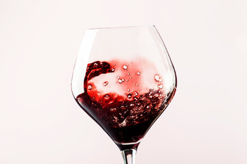 Dry red wine, splash in glass, pink background, defocused in motion image, shallow depth of field