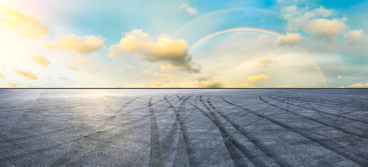 Asphalt road pavement and rainbow sky panorama at sunset