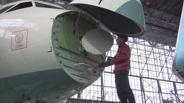Engineer repairs locator passenger aircraft. The plane in the hangar, antenna repair. Aviation. Production of passenger Airliners. 4K