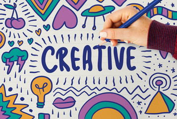 Woman drawing the word creative typography on a board