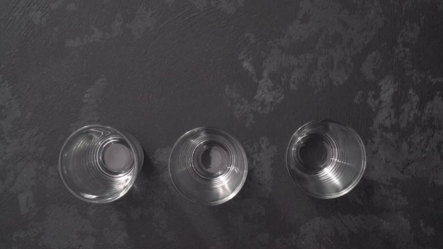 Vodka  pouring from a bottle into a glass in a black background. Pouring vodka in glasses close-up. Vodka being poured into a glass.Top view