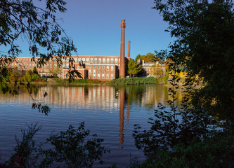 A 19th century textile mill has been renovated for modern use, seen reflected in the neighboring river © mindstorm