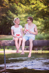 Fototapeta na wymiar couple enjoying watermelon while sitting on the wooden bridge