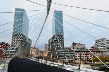 View of a Zubizuri bridge,over the Nervion River, in a cloud day, between the towers of Bilbao, Vizcaya, Spain.
