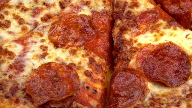 Sliced whole pepperoni pizza spinning video close up