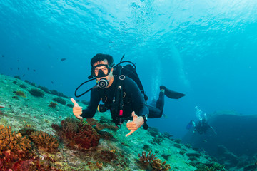 Fototapeta na wymiar SCUBA divers swimming over a colorful tropical coral reef (Similan Islands)