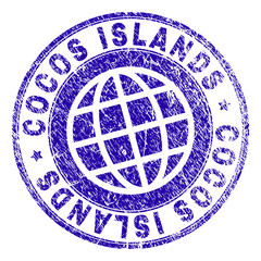 COCOS ISLANDS stamp print with grunge texture. Blue vector rubber seal print of COCOS ISLANDS title with unclean texture. Seal has words placed by circle and planet symbol.