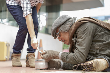 Older dirty homeless man look at money and receive it from donor's hand and donor donate money for...