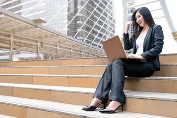 Asian attractive beautiful business woman using her laptop and cerebrating when professional project was successful at outside the office. Business Outdoor Concept.