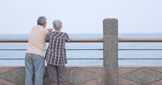 Old couple chatting and looking at the sea together - Powered by Adobe