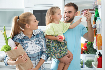 Happy family with products near refrigerator in kitchen