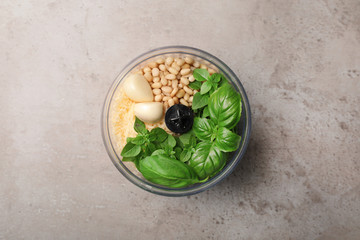 Ingredients for homemade basil pesto sauce in blender container on table, top view