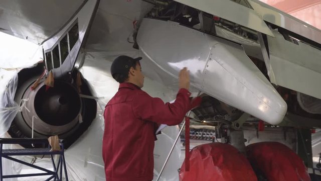 The engineer repairing the aircraft at the factory. Repair of an aircraft wing. Inspection of the fuselage. Passenger plane in the hangar in the repair. Aviation. 4K