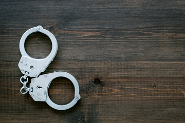 Metal handcuffs on dark wooden background top view copy space