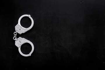 Metal handcuffs on black background top view space for text