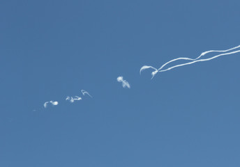Jet airline traces shape in the blue sky