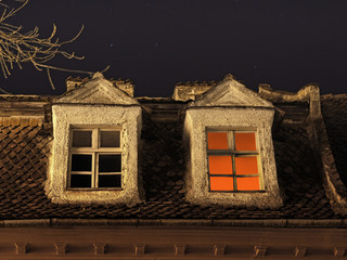 Candle light inside the room, seen on a window under a starry night