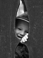 Little kid smile behind wooden fence