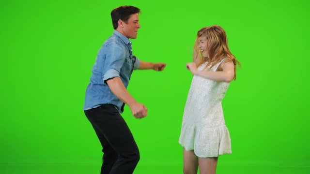 Slow motion couple dances happily over a green screen, jumping and smiling.
