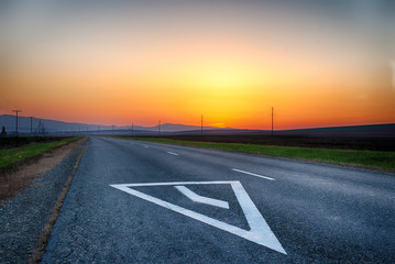 Mountain road. The curve of the road at sunset. Asphalt coating. Bright horizon.