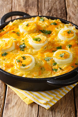 Delicious English Anglesey Eggs main course of boiled potatoes, leek cheese sauce, and eggs closeup. vertical