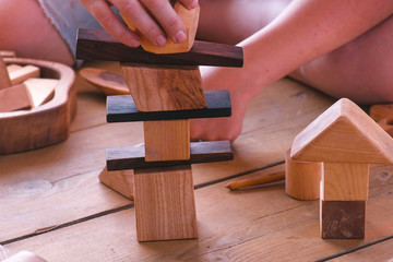 Woman is building a tower from wooden blocks. Close-up hands.