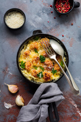 Meatballs with cheese and cream sauce in cast iron pan on gray vintage background. Top view.