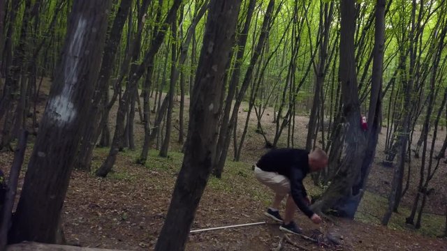Man making firecamp in the forest. Male firewood Campfire alone outdoor In the woods. Hiker resting after trekking and starting bonfire
