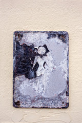 Old metal plate with sign “For men” on a stucco wall.