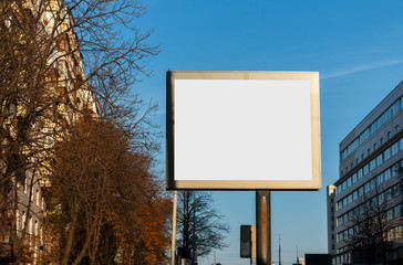 The big white billboard in the city during day time. Billboard mock-up on the blue sky and city background.