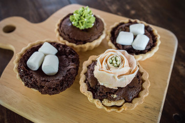 Close-up of Assorted mini brownie tart serving on the wooden table.