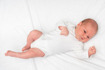 Newborn baby is lying on back on white blanket