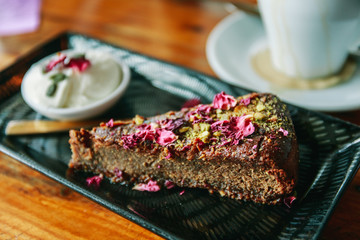 cup of coffee and piece of cake with cream on wood table