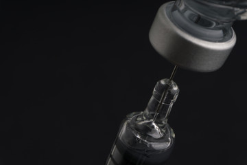 Medical syringe and vial on dark background with selective focus and crop fragment