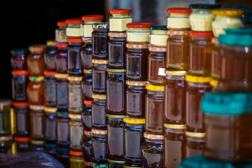 Banks with honey and jam are columns and rows in the window. Souvenirs for tourists in Georgia, yellow and red honey, jam from cones