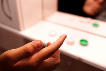 Focus on contact lens on finger of young handsome teen man young male . Close-up Of Young Man Holding Contact Lens On Finger Eyesight and eyecare concept. Ophtalmology concept versus wearing glasses